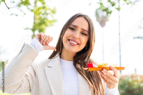 Photos Young pretty woman holding sashimi at outdoors proud and self-satisfied