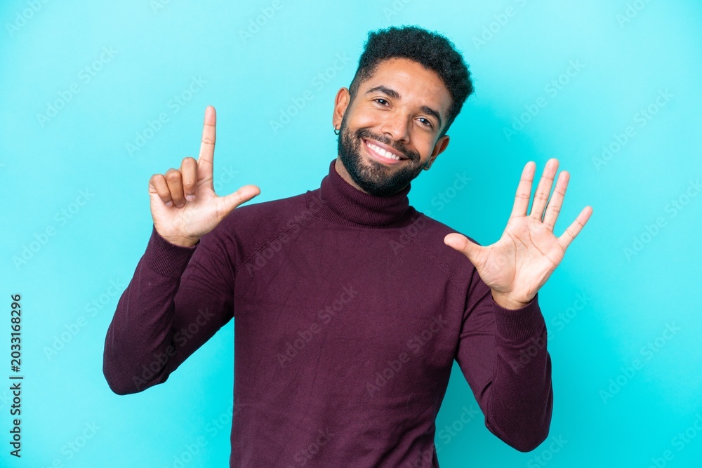 Naklejka premium Young Brazilian man isolated on blue background counting seven with fingers