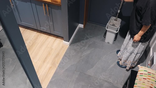 A teenager is mopping floor indoors using a flat mop performing home cleaning tasks, illustrating daily household maintenance and cleanliness concepts