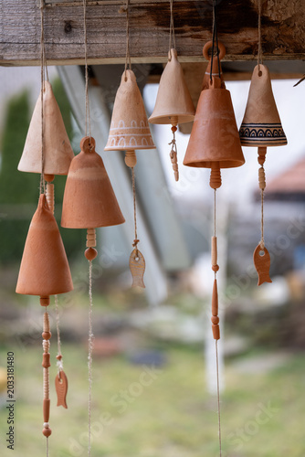 Handmade ceramic wind chimes hanging outdoors. Traditional clay craftsmanship with decorative fish ornaments, shallow depth of field and natural light.
