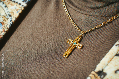 Obraz na plátně Elegant gold cross pendant with a small blue gemstone on a delicate chain