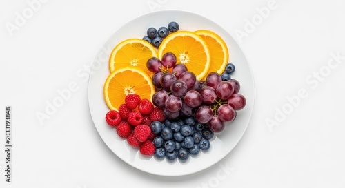 A colorful selection of fresh organic fruits including sliced oranges, grapes, and berries artfully arranged on a white ceramic plate, raspberry, breakfast, bowl