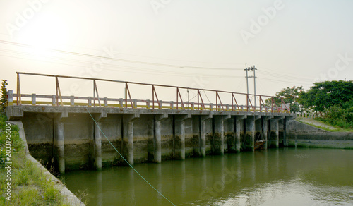 Foto Concrete bridge and sluice gate structure over green river
