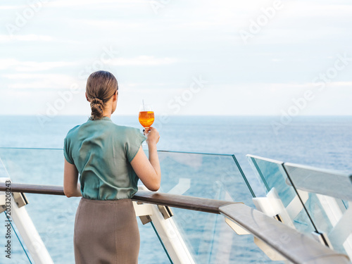 Canvastavla Fashionable woman with a glass of drink standing on the empty deck of a cruise ship against the backdrop of sea waves