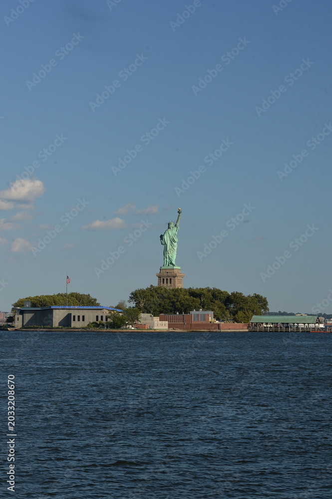 Obraz premium Statue Of Liberty Stands Tall Over Bustling Harbor With City In Background new york