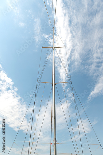 A yacht mast against a blue sky. Vertical photo.