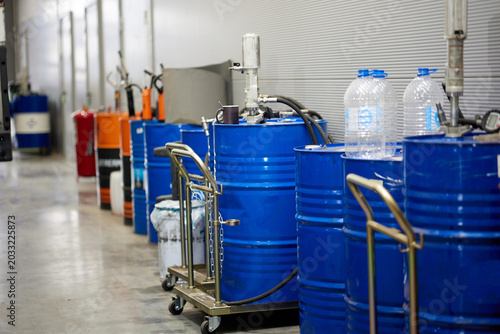 nside a busy automotive service center, blue barrels of oil stand in an orderly manner. The scene depicts the essential supplies needed for vehicle maintenance, ensuring a professional atmosphere.