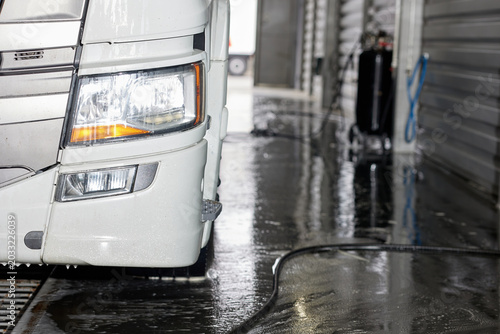 This image features a white truck parked at a car wash specifically designed for larger vehicles. The facility showcases ample space and facilities catering to suvs and trucks.