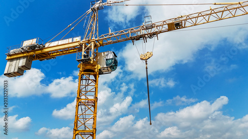 Cuadro en lienzo Yellow crane dominates blue sky with white clouds
