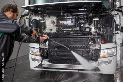 An expert cleaner meticulously washes a white truck using a contactless washer in a modern, spacious car wash facility. The clean environment highlights efficiency and attention to detail.