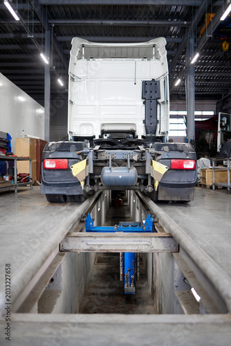 This image depicts a sleek, modern truck resting strategically on a maintenance pit. Perfect for illustrating vehicle inspections, repairs, and automotive services in a contemporary garage setting.