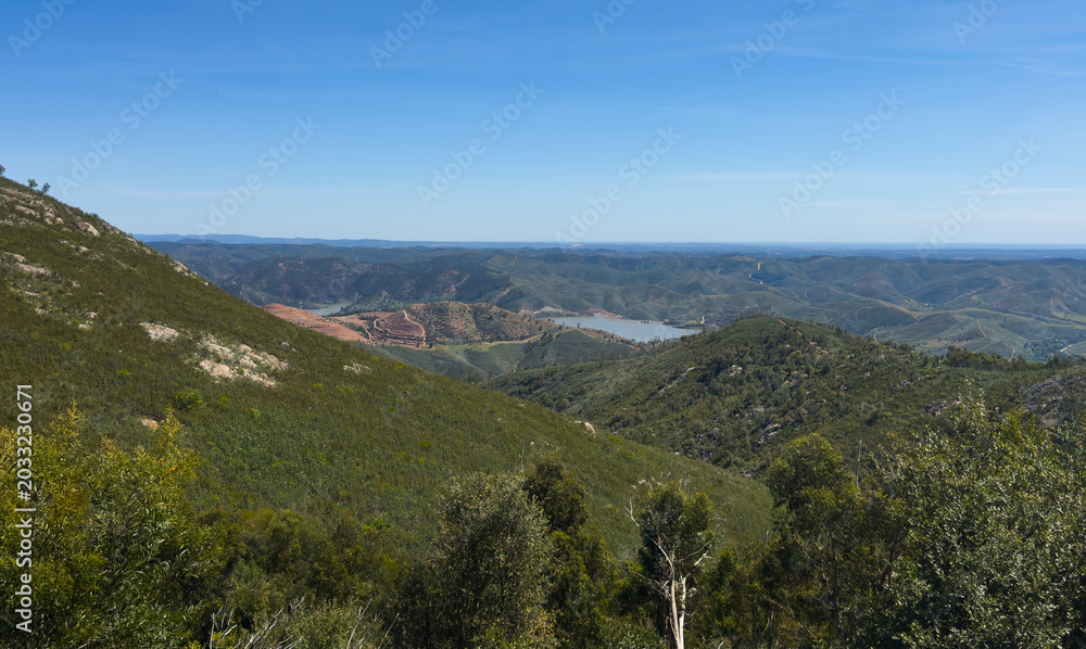 Fototapeta premium Lake with trees and a hill formation on the horizon.