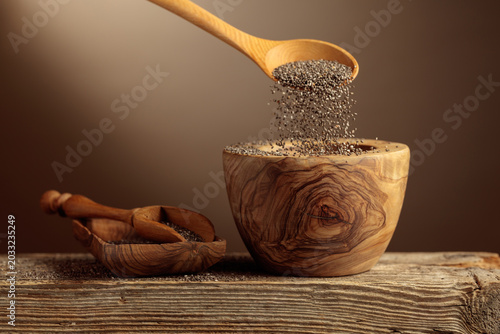 Chia seeds is poured into a wooden bowl.