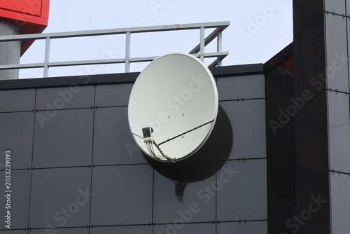 Konstfotografi Close-up view of a white parabolic satellite dish affixed to a dark grey modern building facade