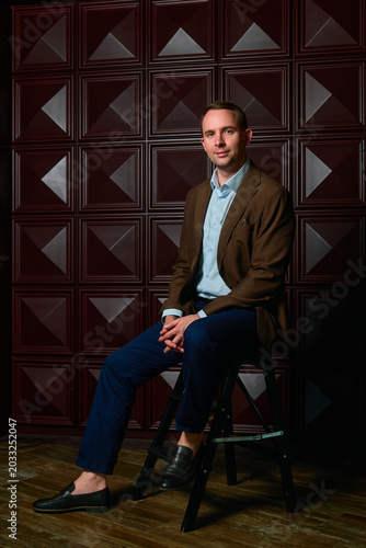 a man in a three-piece suit against a dark wall