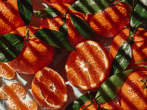 Vibrant oranges, some whole and some sliced, glisten under natural light, showcasing their juicy texture and bright color.