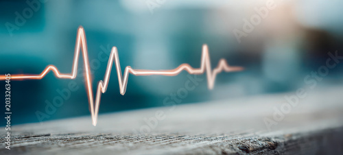 Modern heartbeat line displayed on a surface with a blurred background during daylight hours