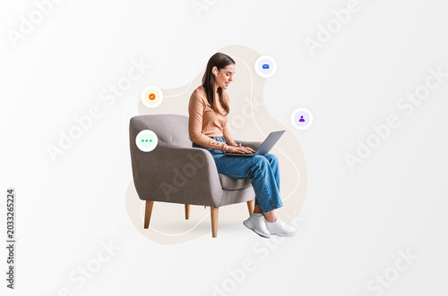 Photos A woman sits on a gray chair at home working on a laptop