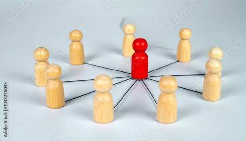 Red wooden figure connected by lines to surrounding natural wood figures on a gray background, symbolizing leadership, teamwork, and network communication.