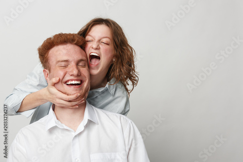 Canvas Print Happy young couple in white shirts playfully interact on light background