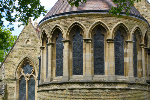 Fotografia Gothic revival church apse featuring arched stained glass windows and stone architecture details