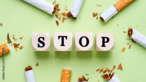 Wooden blocks spelling stop with broken cigarettes concept of quitting smoking tobacco addiction prevention health awareness nicotine cessation campaign motivational message