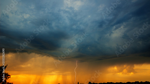 Lightning strike from rain clouds on the horizon line in the evening. Web banner.