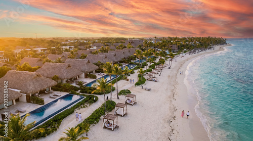 A tropical paradise resort at sunset, with overwater bungalows, a pristine beach, and a swimming pool	