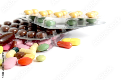 Many different multi-colored medicines lie on a white background.
