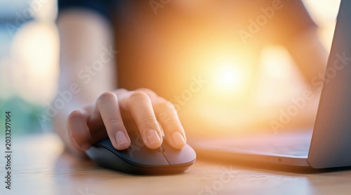 Close up of person hand using wireless mouse on wooden desk with laptop in warm light