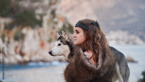 Canvastavla A woman hugs a Siberian Husky dog near the coastline