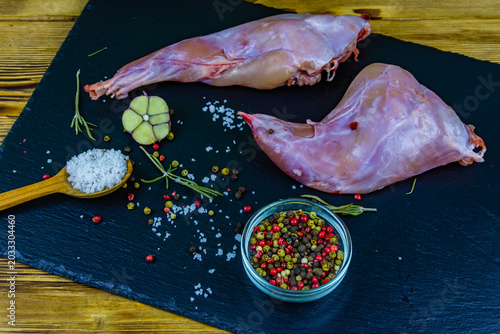 Rabbit meat with pepper, rosemary, salt and garlic on a slate board