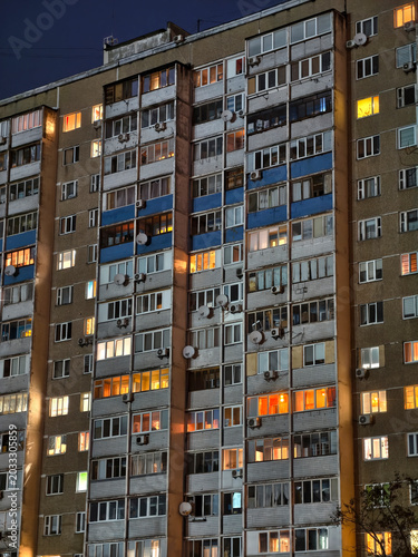 Tall building in city at night. Apartment building glowing at night. City apartments building glowing light