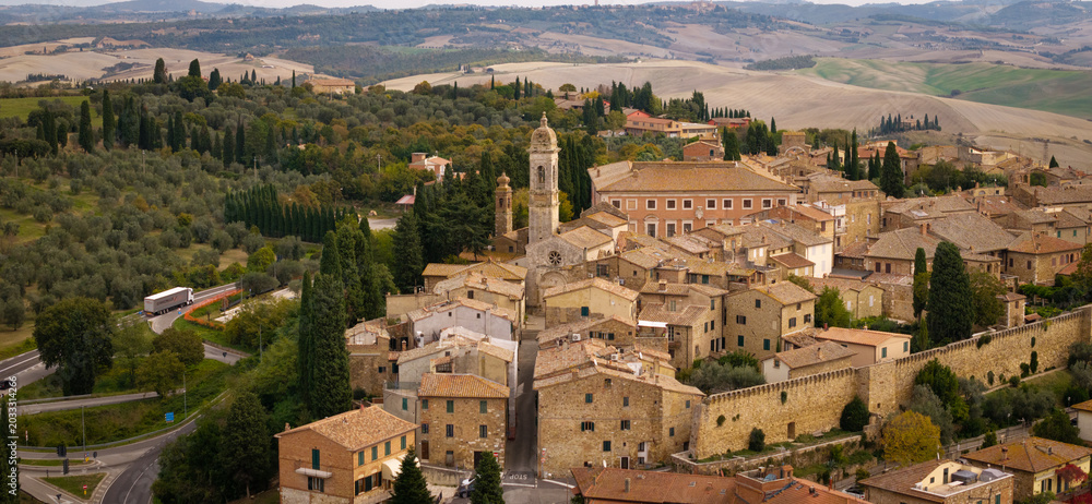 Obraz premium Aerial drone view of San Quirico d'Orcia borgo with red tile roofs. Panoramic view of historic Tuscan village with rolling hills background of Val d'Orcia valley, Italy. countryside of Tuscany