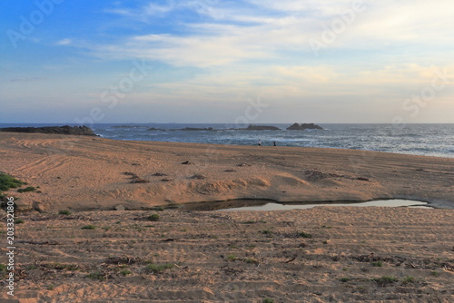 A sandy beach with water and a cloudy sky
