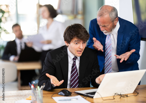 Photos Strict mature man boss scolding young guy office worker for improper operation o