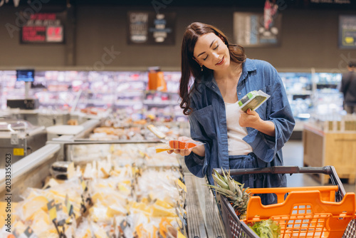 Принти на полотні Woman comparing packaged deli meat and cheese options, making healthy choices wh