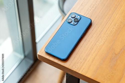 Foto Blue smartphone on wooden table near window