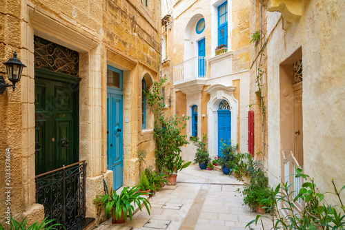 Cozy street and traditional colorful wooden balconies in Birgu, Malta