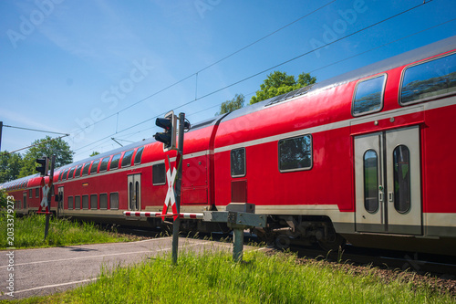 Ein Zug mit Doppelstockwagen fährt an einem Bahnübergang vorbei