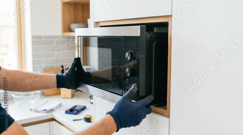 Professional Technician Installing New Microwave Oven Into Custom Kitchen Cabinetry