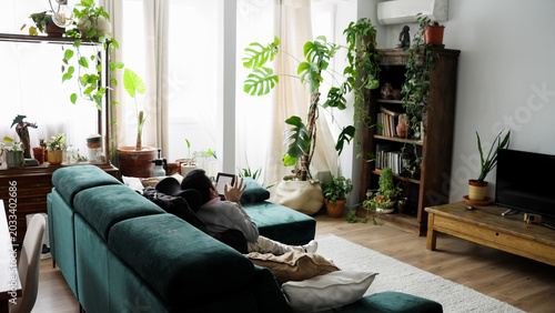 Fotografie Young man living with spina bifida comfortably relaxing on a sofa, reading an e