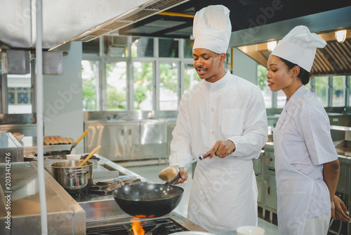 Culinary training with students practicing wok cooking skills and teamwork in professional school kitchen