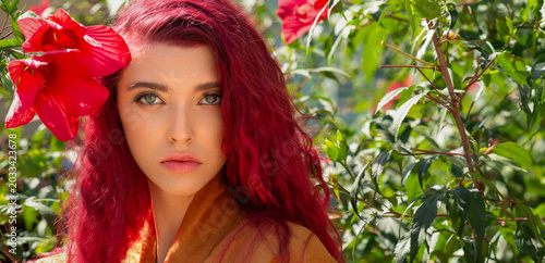 Beautiful young woman with long curly hair and grey-blue eyes. Portrait of a beautiful red-haired model with perfect skin and long eyelashes looking at the camera. Real photo