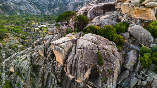 Billede på lærred Drone view over huge rocky mountain formations surrounded by lush green pine tre