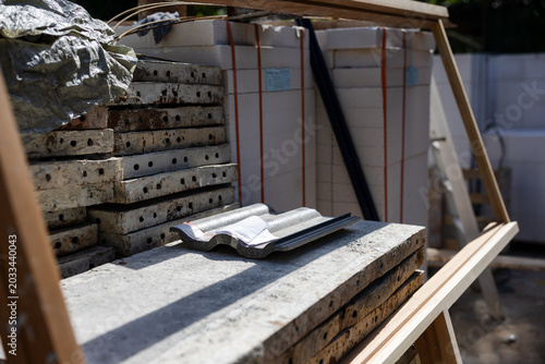 Tableau sur toile A construction site featuring stacked building materials, including tiles and concrete slabs, organized in a wooden frame under natural lighting