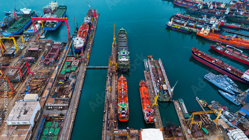 Drone view over a large ship repair yard featuring heavy cranes and massive docks