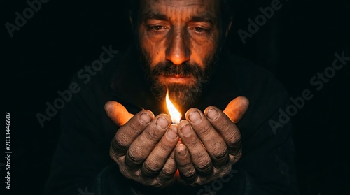 Middle aged bearded man holding a small flame in his hands