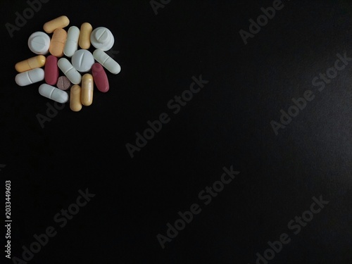 Schilderij op canvas Assorted pills, tablets, capsules isolated on black background with copy space for drugs, medications, prescription medicines, medical treatments, vitamins, pharmaceuticals, and healthcare concepts