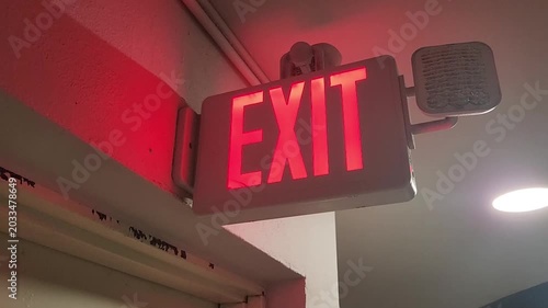 Indoor illuminated emergency exit sign attached above a doorway providing safety guidance and evacuation direction in a building environment.